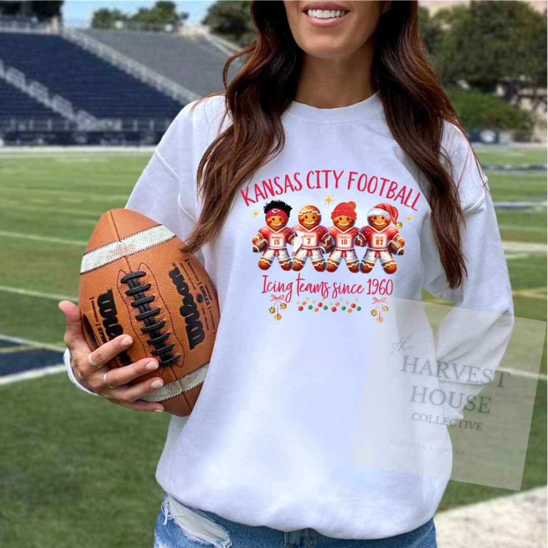 Person wearing a white sweatshirt with 'Kansas City Football' design, holding a football on a sports field.