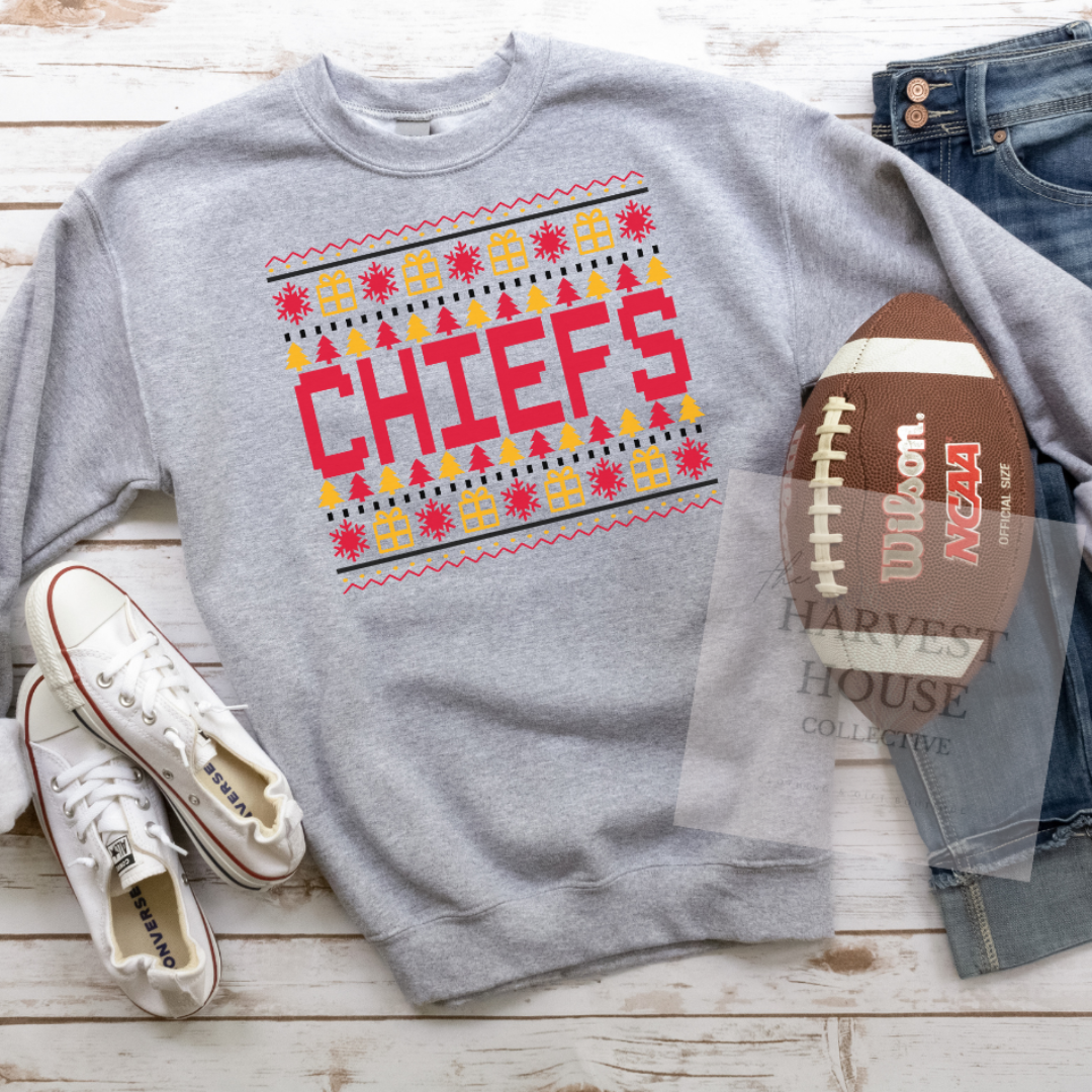 Gray sweatshirt with 'CHIEFS' design, white sneakers, jeans, and a football on a wooden surface.