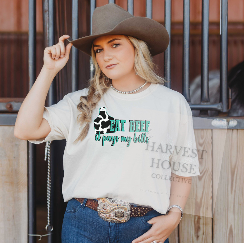 Woman wearing a white t-shirt with text and graphics, standing in front of wooden stalls.