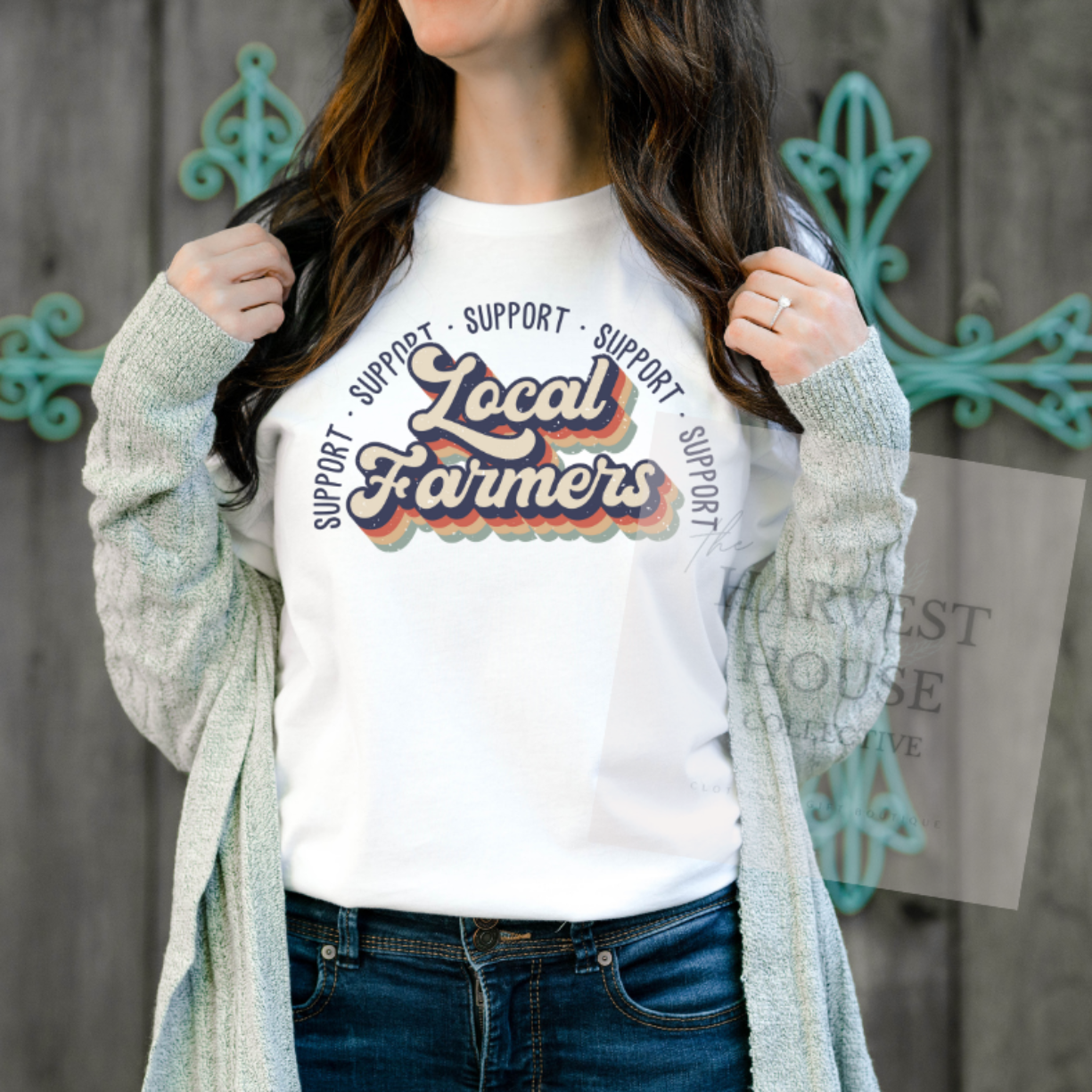 Person wearing a white t-shirt with 'Support Local Farmers' text, standing against a wooden background.