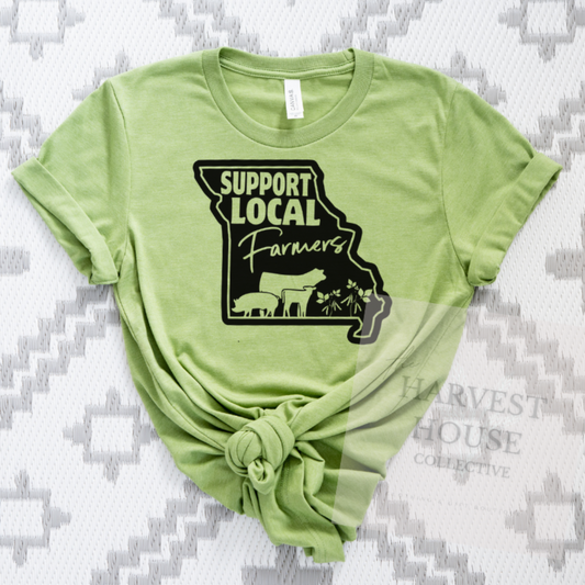 Green t-shirt with 'Support Local Farmers' graphic on a textured gray background