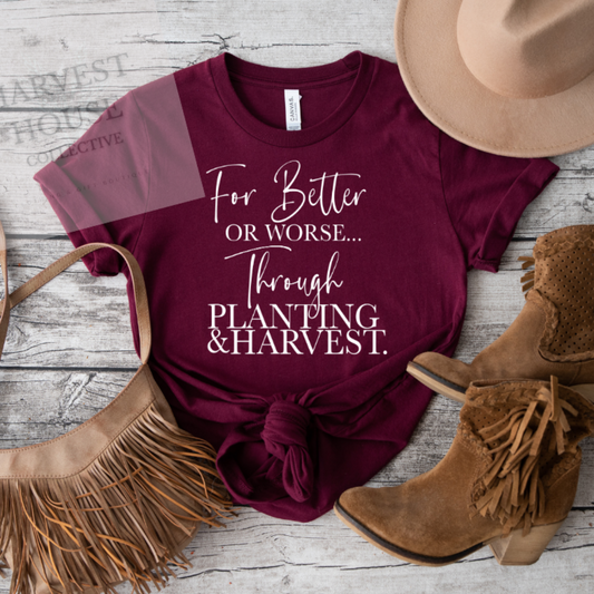 Maroon t-shirt with text, cowboy hat, boots, and handbag on a wooden surface